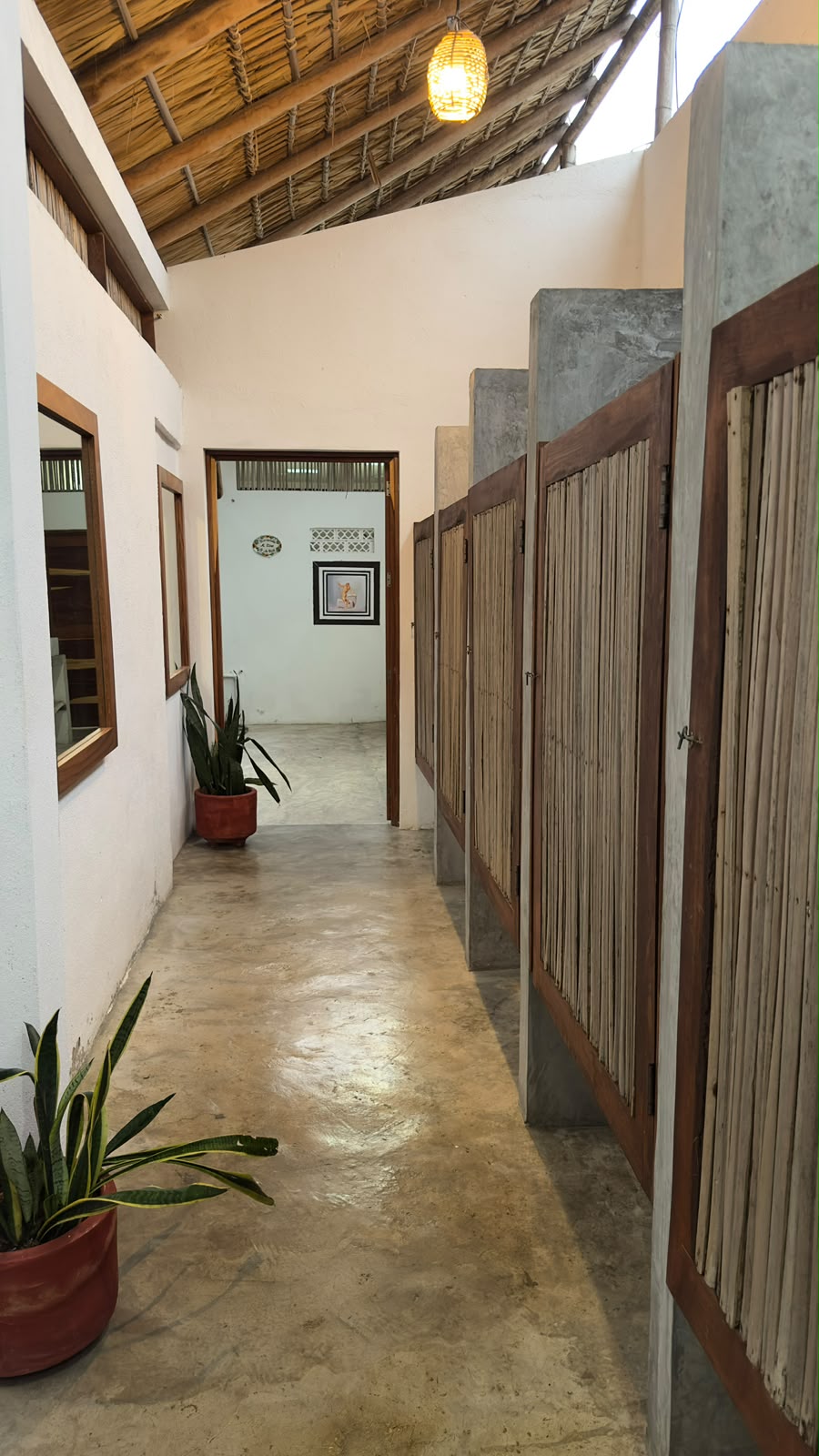 Pasillo de baños con puertas de bambú y techos de palma