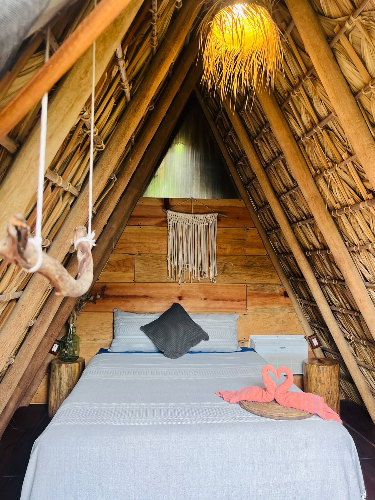 Interior de teepee con cama, macramé y lámpara de palma